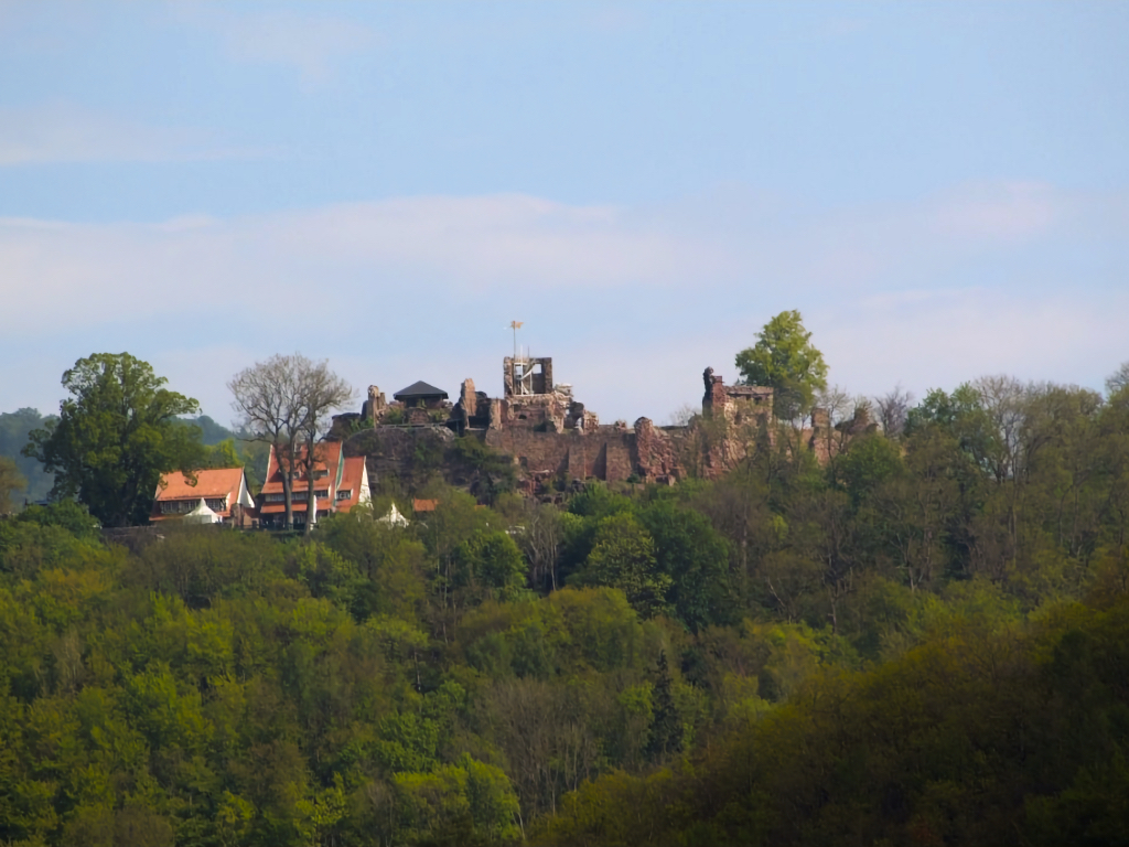 Schöner Blick auf eine gut erhaltene Burgruine, die auf einem bewaldeten Berg thront.