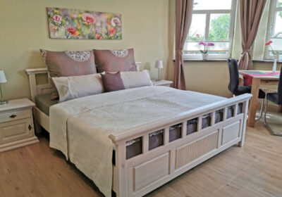 Ein Foto vom Schlaf- und Wohnbereich einer Ferienwohnung mit einem großen beigefarbenen Doppelbett.