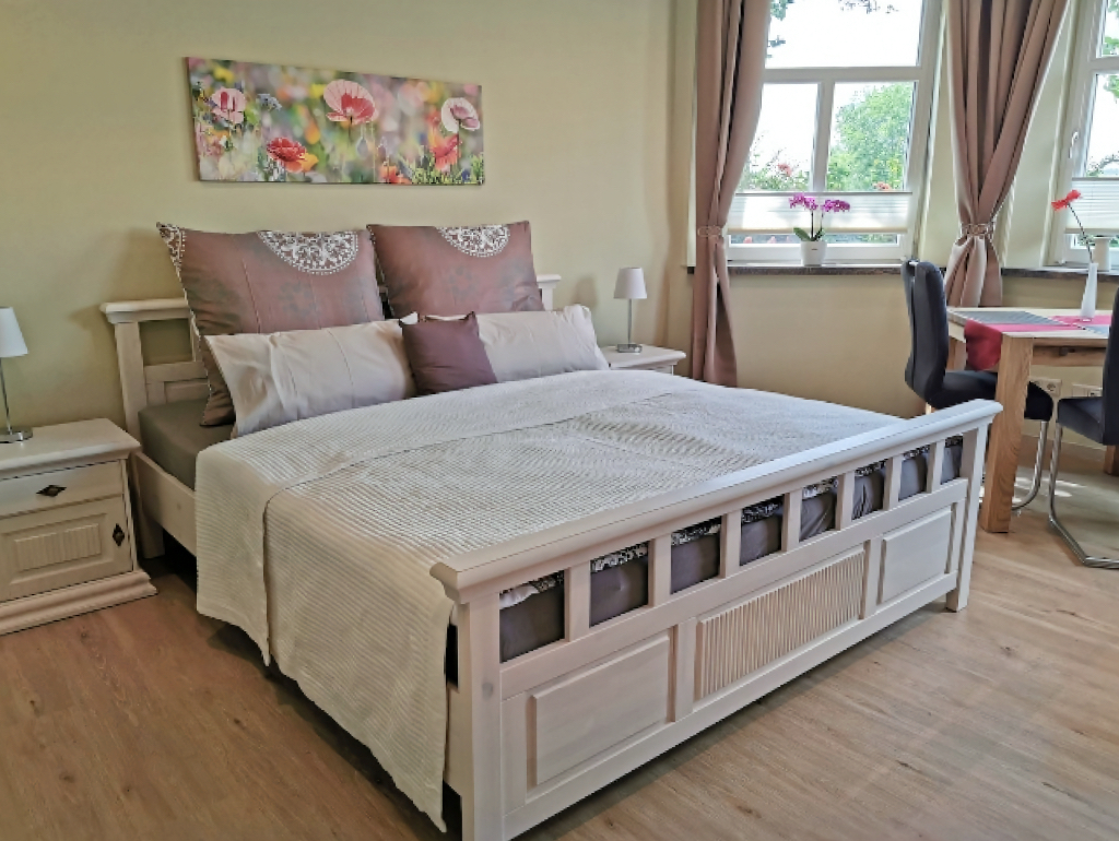 Ein Foto vom Schlaf- und Wohnbereich einer Ferienwohnung mit einem großen beigefarbenen Doppelbett.