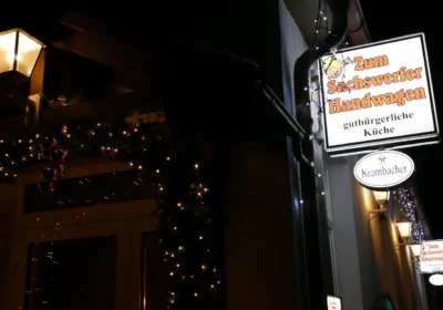 Außenansicht der Gaststätte "Zum Sachswerfer Handwagen" bei Nacht, mit beleuchtetem Werbeschild