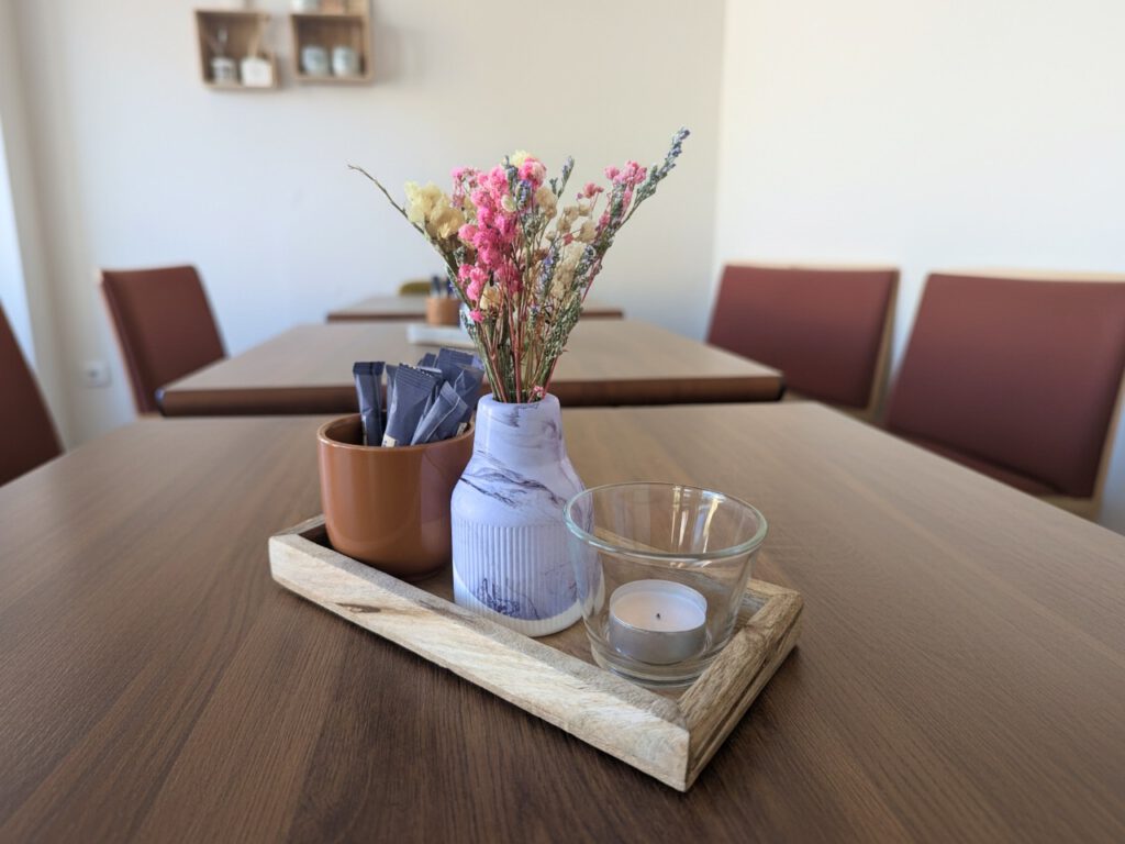 Tischdekoration im Fräulein Fuchs und Hummel: Holztablett mit Trockenblumen in einer Marmor-Vase, Teelicht und Zuckersticks im Becher.