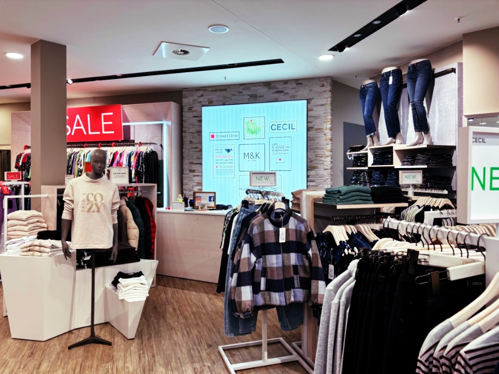 Mode Koch in der Marktpassage Nordhausen: Hell erleuchteter Laden mit Cecil- und Street-One-Schild, Sale-Bereich, Jeans-Wand und Schaufensterpuppe im „COZY“-Sweatshirt.